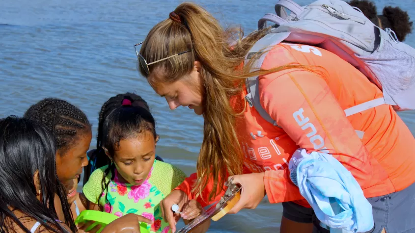 group of kids looking at creature by water