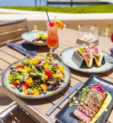 A table topped with plates of food next to a body of water