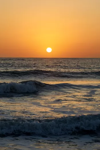 The sun is setting over the ocean waves