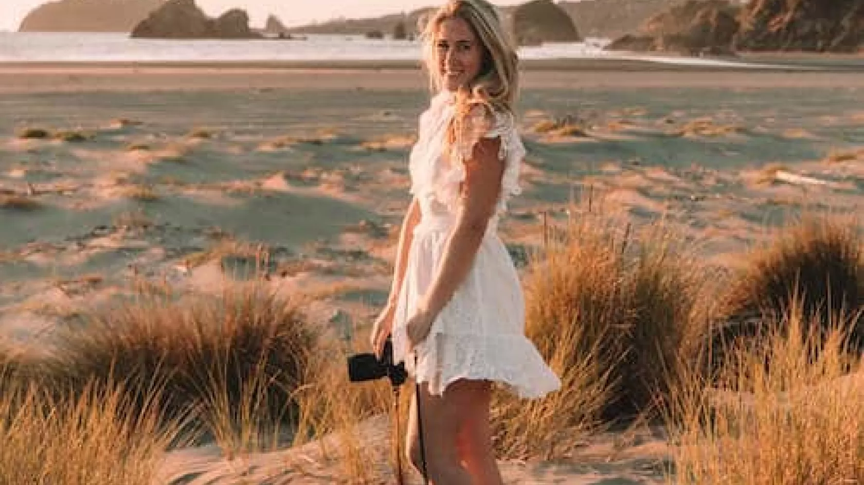 a photo of a woman standing with a camera lens on the beach