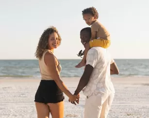 A family poses on the beach together at sunset